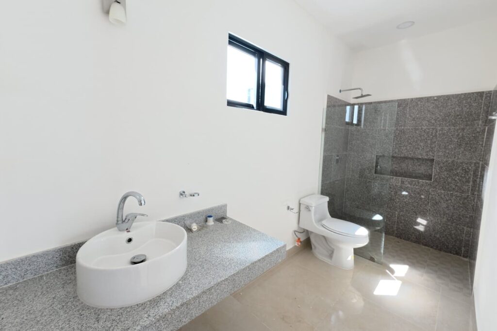 Baño principal con acabados de mármol en propiedad en Dzityá Mérida